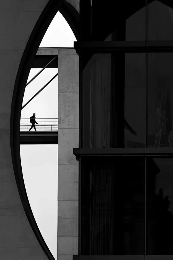 A Person Walking on a Bridge Attached to a Modern Building in City